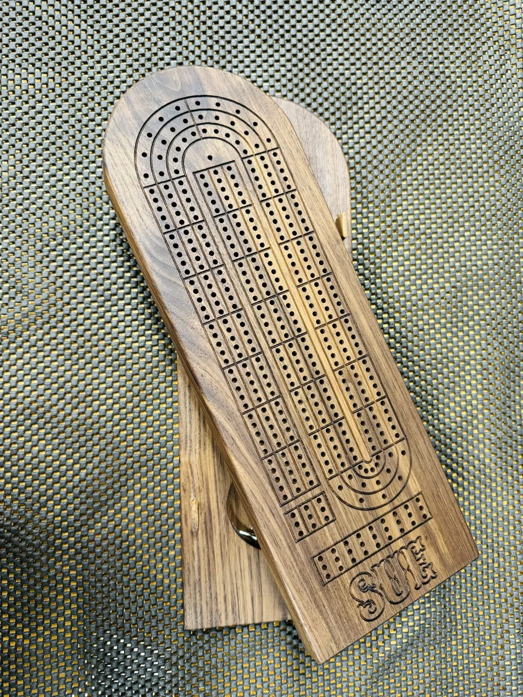 Personalized walnut cribbage board with engraved scoring tracks and a hinged base