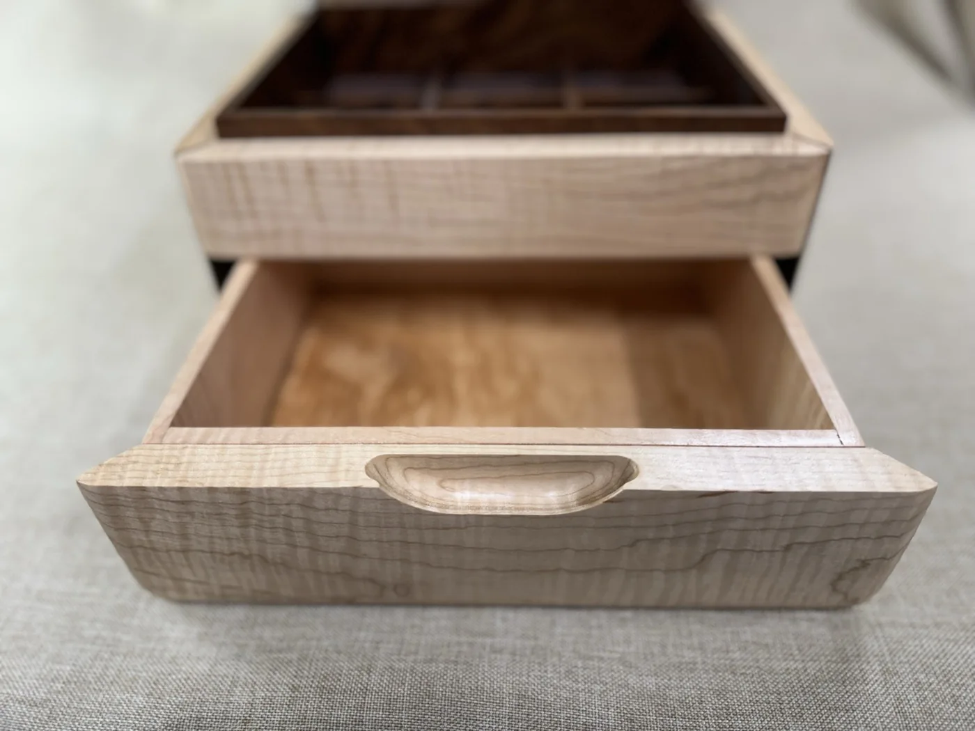 Close-up of the wooden jewellery box drawer and its curved finger pull
